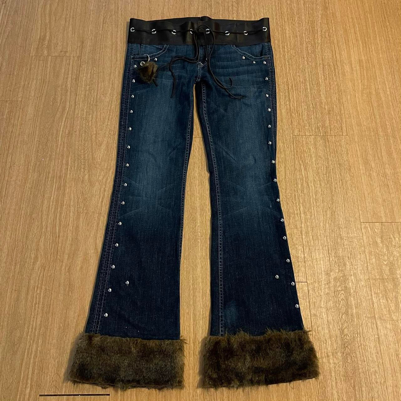 ୨୧ reworked y2k OOAK lowrise flare jeans with thick contrast stitching, eyelets, studs, faux fur cuffs + keychain, and faux leather lace up waist band