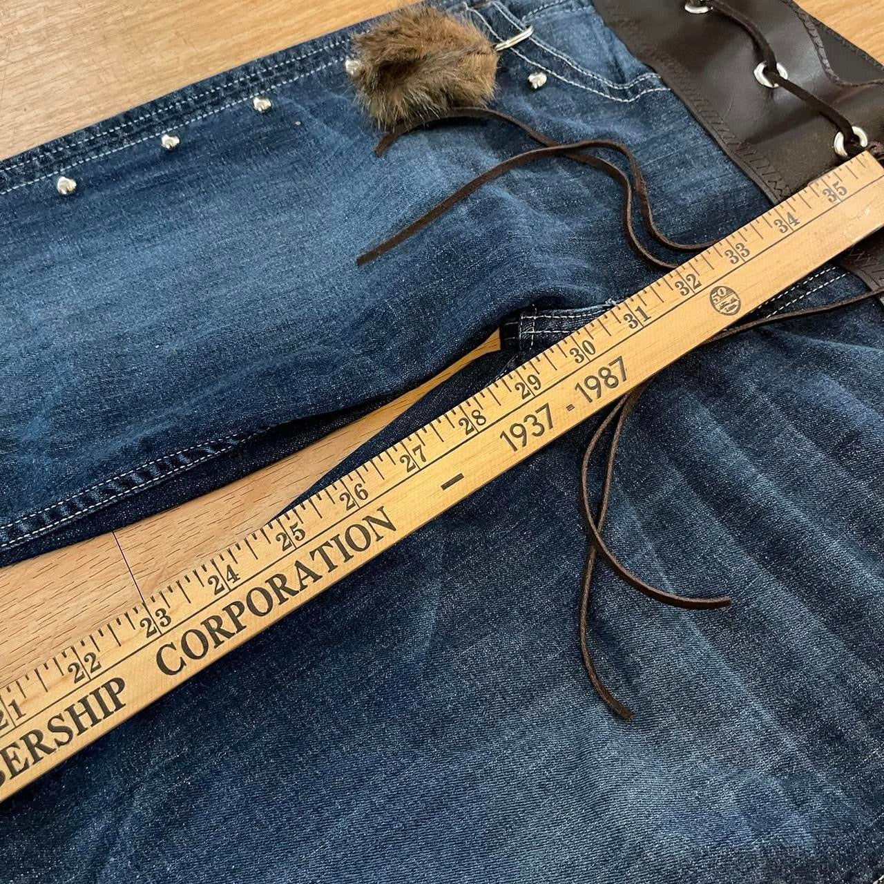 ୨୧ reworked y2k OOAK lowrise flare jeans with thick contrast stitching, eyelets, studs, faux fur cuffs + keychain, and faux leather lace up waist band