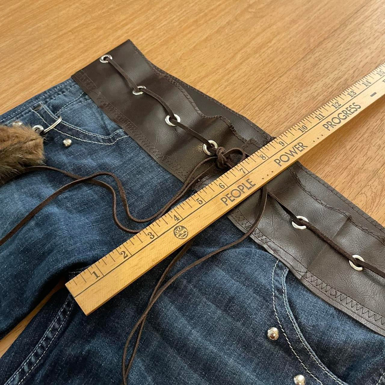 ୨୧ reworked y2k OOAK lowrise flare jeans with thick contrast stitching, eyelets, studs, faux fur cuffs + keychain, and faux leather lace up waist band