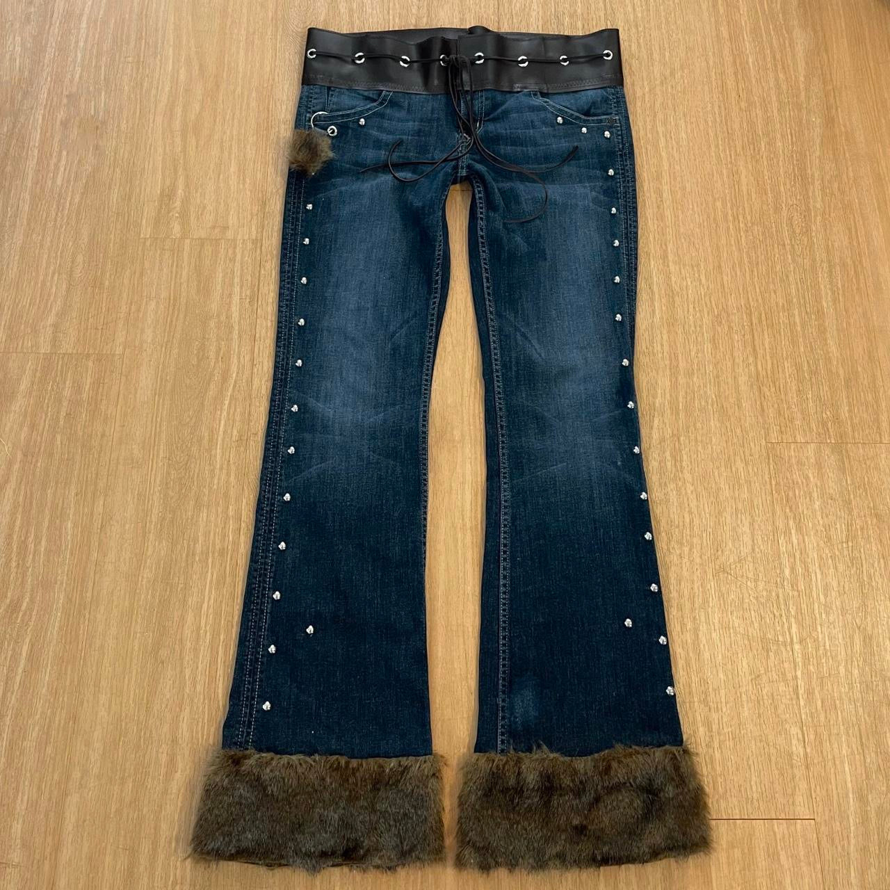 ୨୧ reworked y2k OOAK lowrise flare jeans with thick contrast stitching, eyelets, studs, faux fur cuffs + keychain, and faux leather lace up waist band