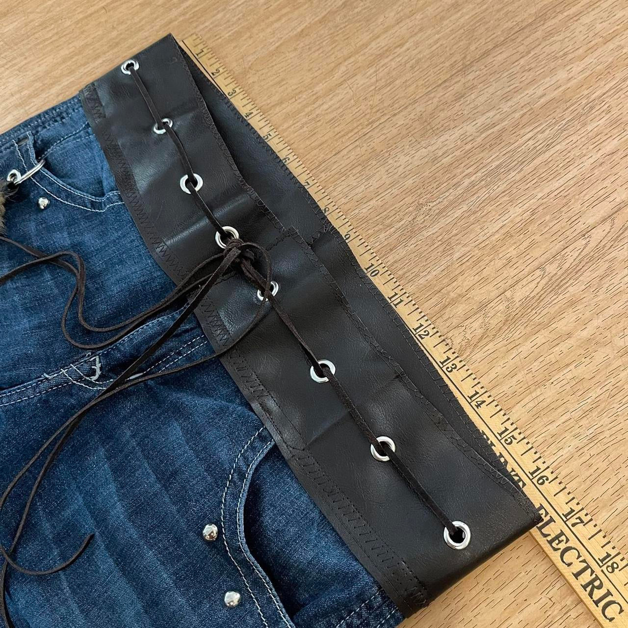 ୨୧ reworked y2k OOAK lowrise flare jeans with thick contrast stitching, eyelets, studs, faux fur cuffs + keychain, and faux leather lace up waist band