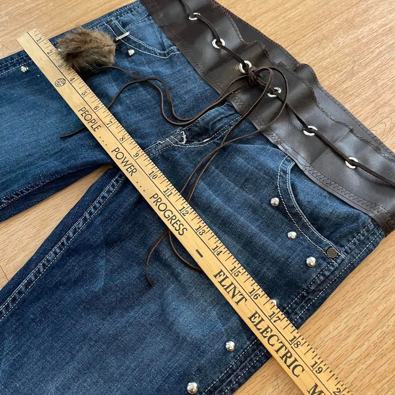 ୨୧ reworked y2k OOAK lowrise flare jeans with thick contrast stitching, eyelets, studs, faux fur cuffs + keychain, and faux leather lace up waist band