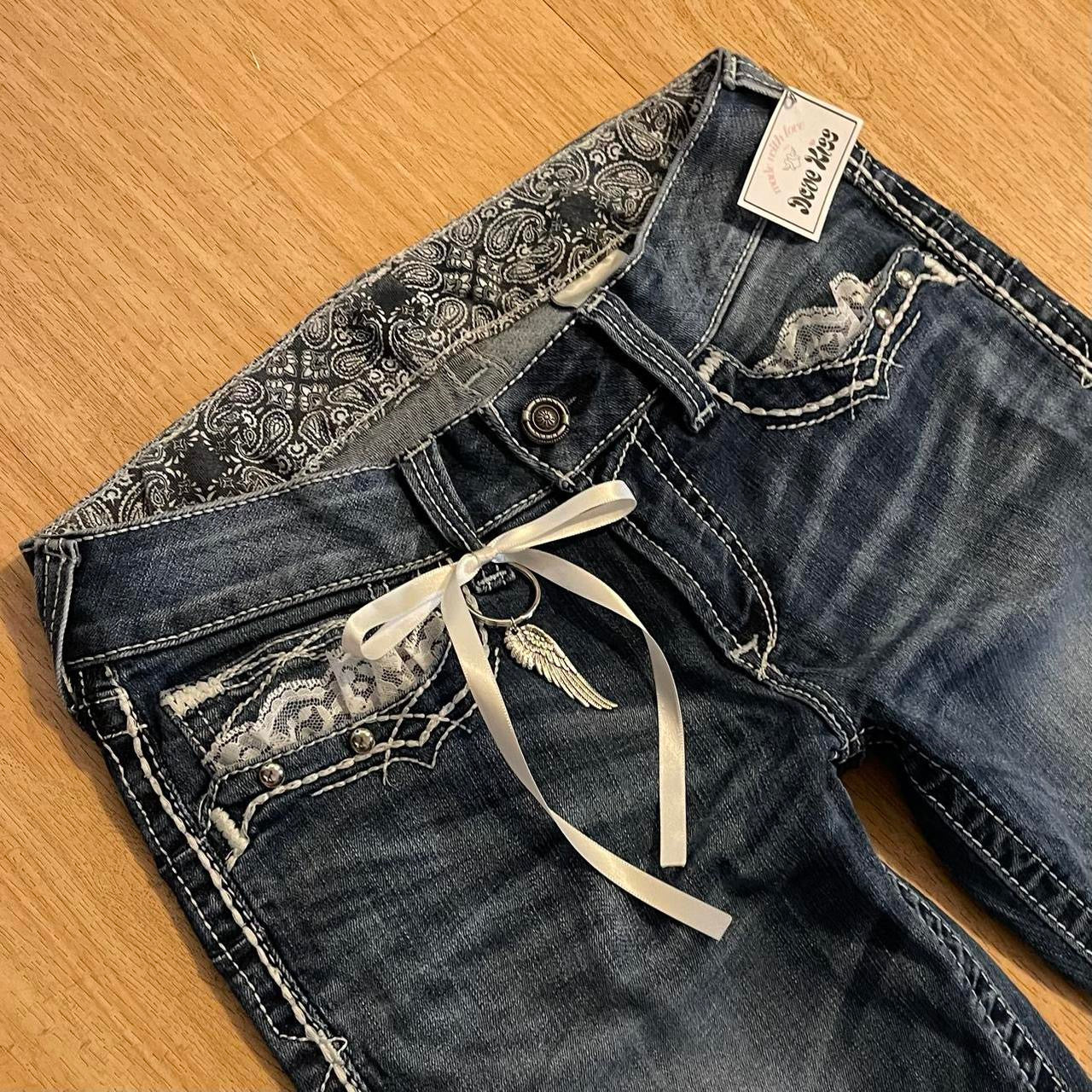 ୨୧ reworked y2k angel princess ooak white ribbon flare ariat jeans with thick contrast stitching, angel wing charm, studs, lace cuffs, lace trim & bows